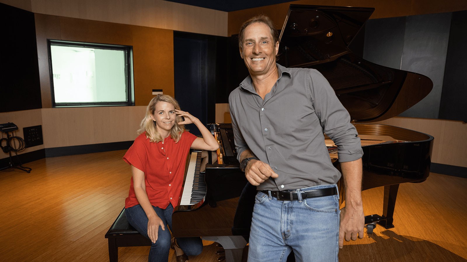 Aoife O’Donovan sits at a grand piano in Full Sail’s Audio Temple. Darren Schneider leans against the piano.