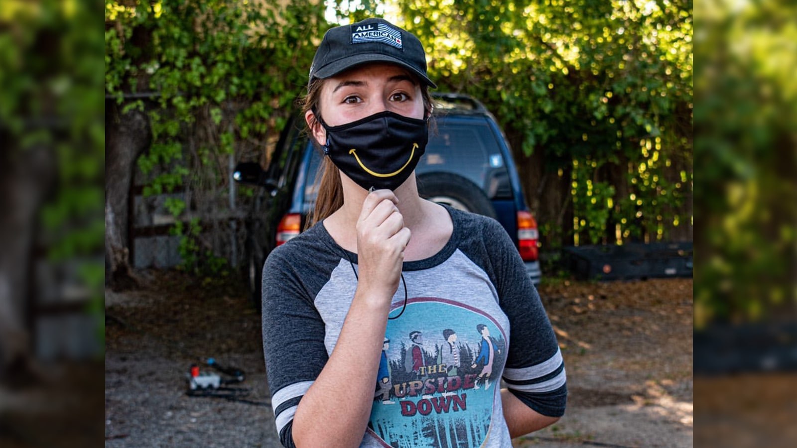 Paola Beck Gisler stands wearing a black mask with a yellow smile.