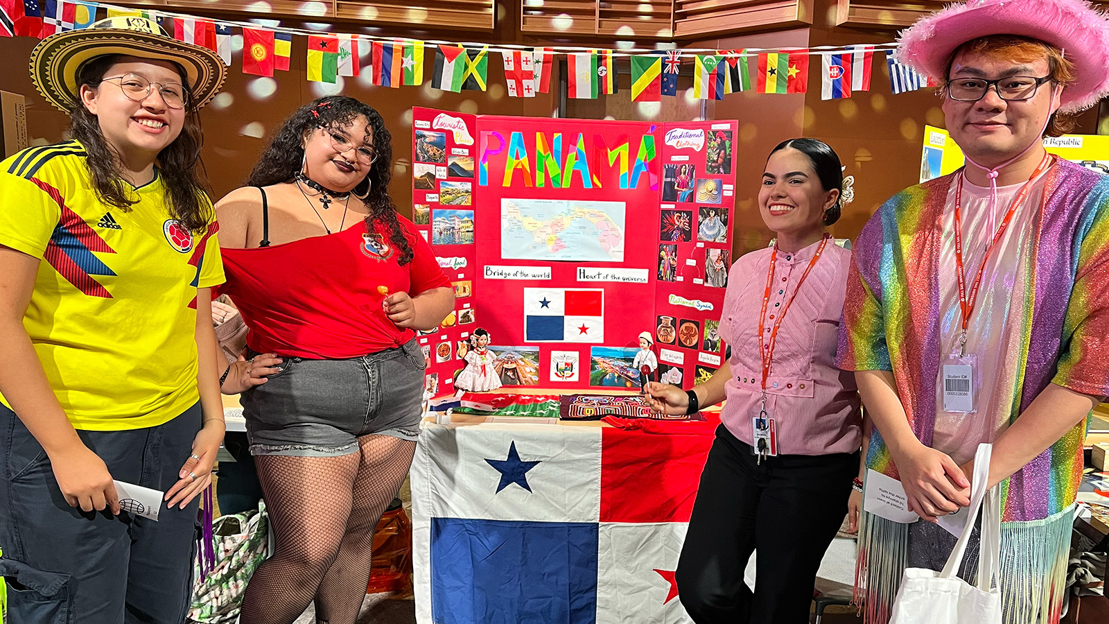 A group of smiling students stand in front of a colorful exhibit about Panama.