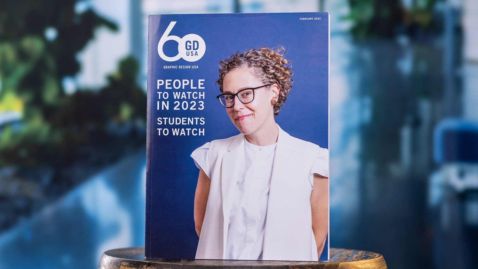 The February 2023 print edition of ‘Graphic Design USA.’ The cover features a smiling designer and text saying “People to Watch in 2023: Students to Watch.”