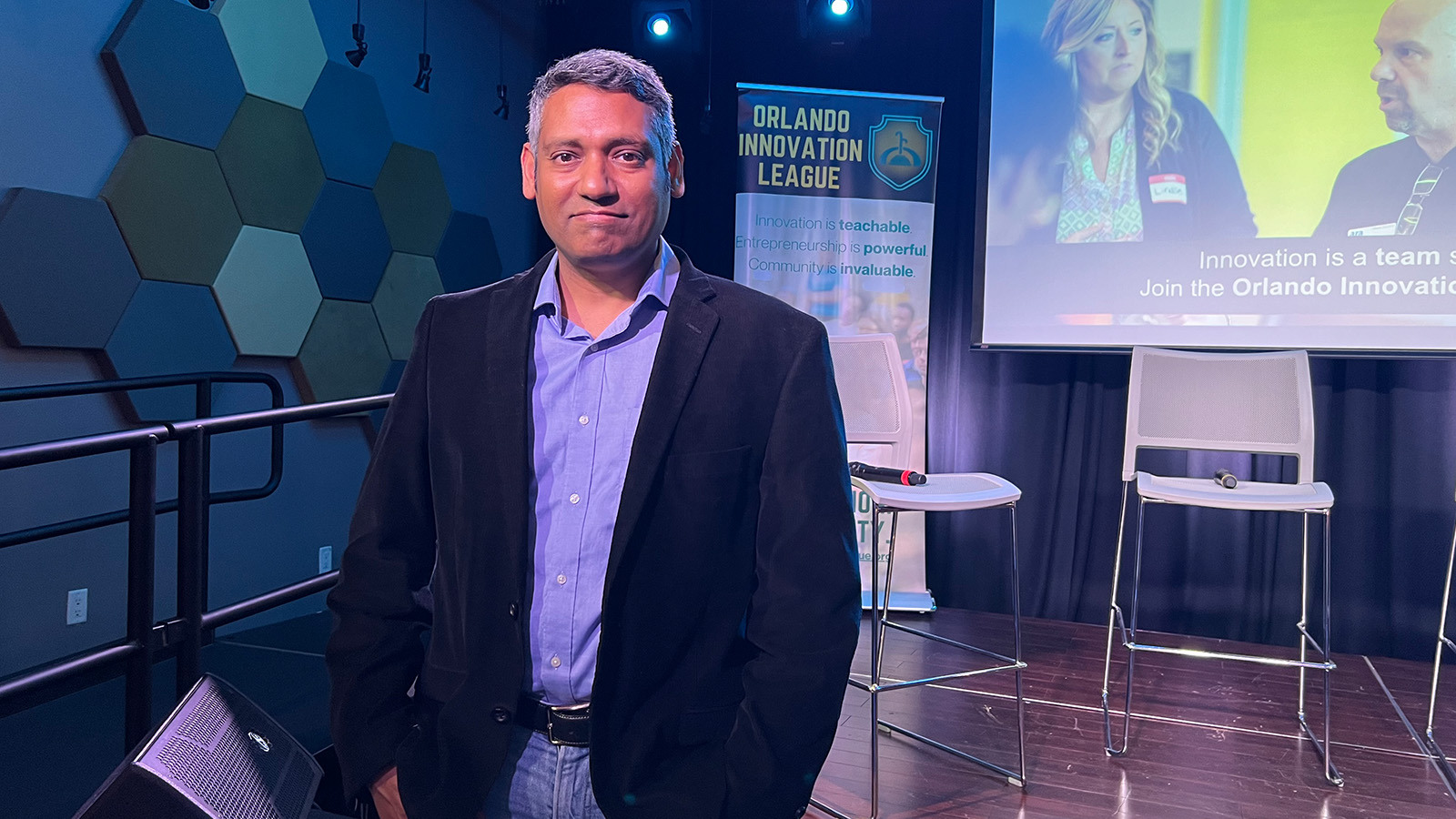 Rajiv Menon, founder of the Orlando Innovation League, poses in front of a stage at the Full Sail Treehouse.