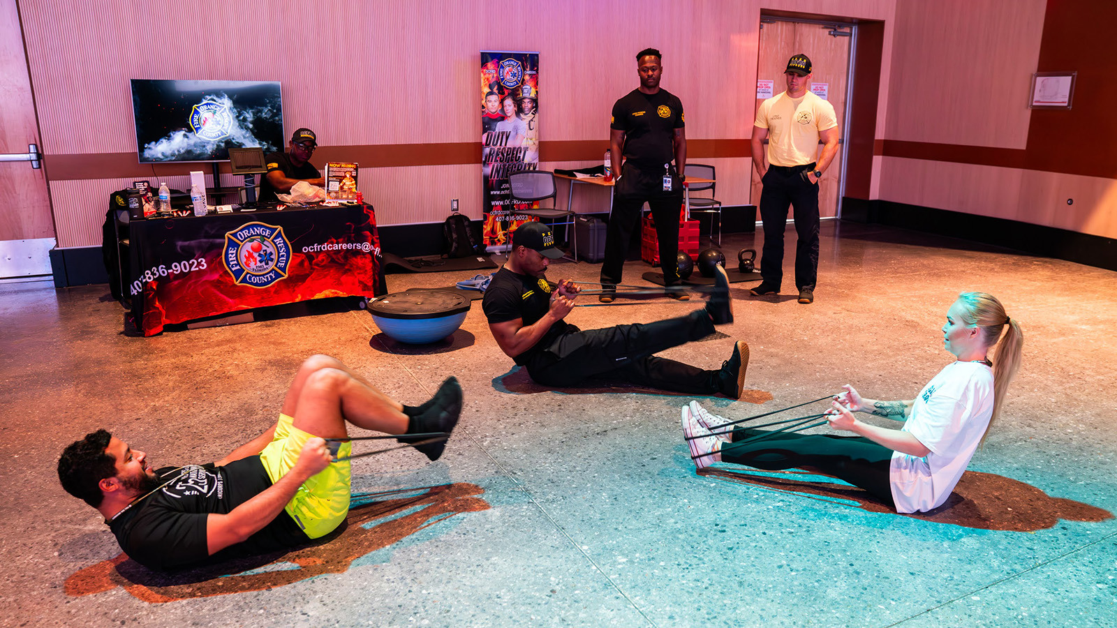 Two staff members take part in a bootcamp style workout instructed by a member of the Orange County Fire Rescue.