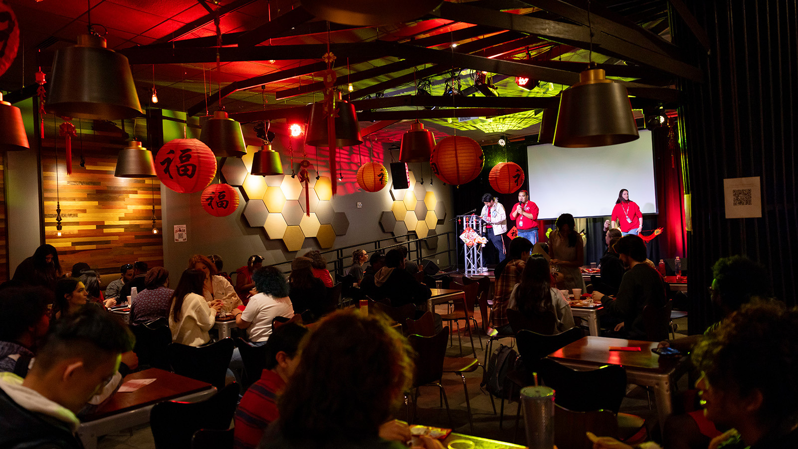 A group gathered at Full Sail's Treehouse, guests sitting down and the hosts on stage. The room is dimly lit and decorated with red paper lanterns for the Lunar New Year.