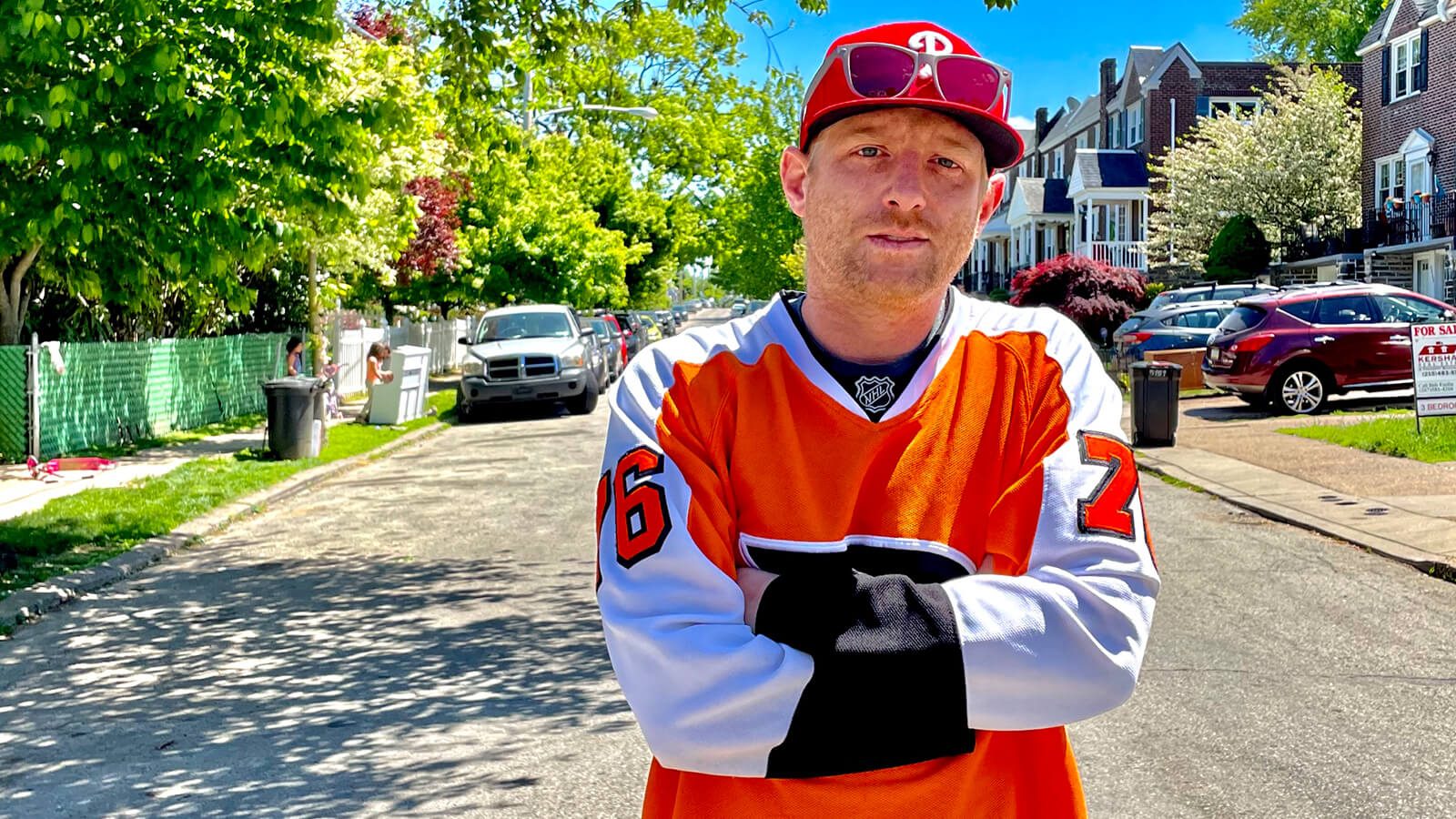 Full Sail Film Production MFA grad Panda Lord in an orange hockey jersey on a residential Philadelphia street.