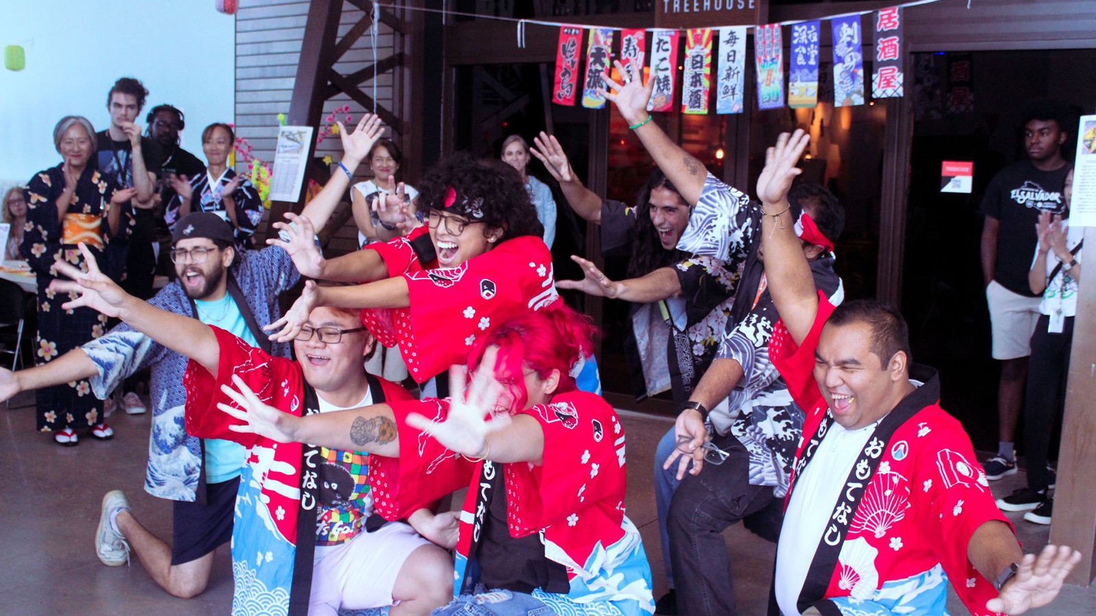A crowd of students pose for the camera in front of the Treehouse wearing colorful traditional Japanese clothing.