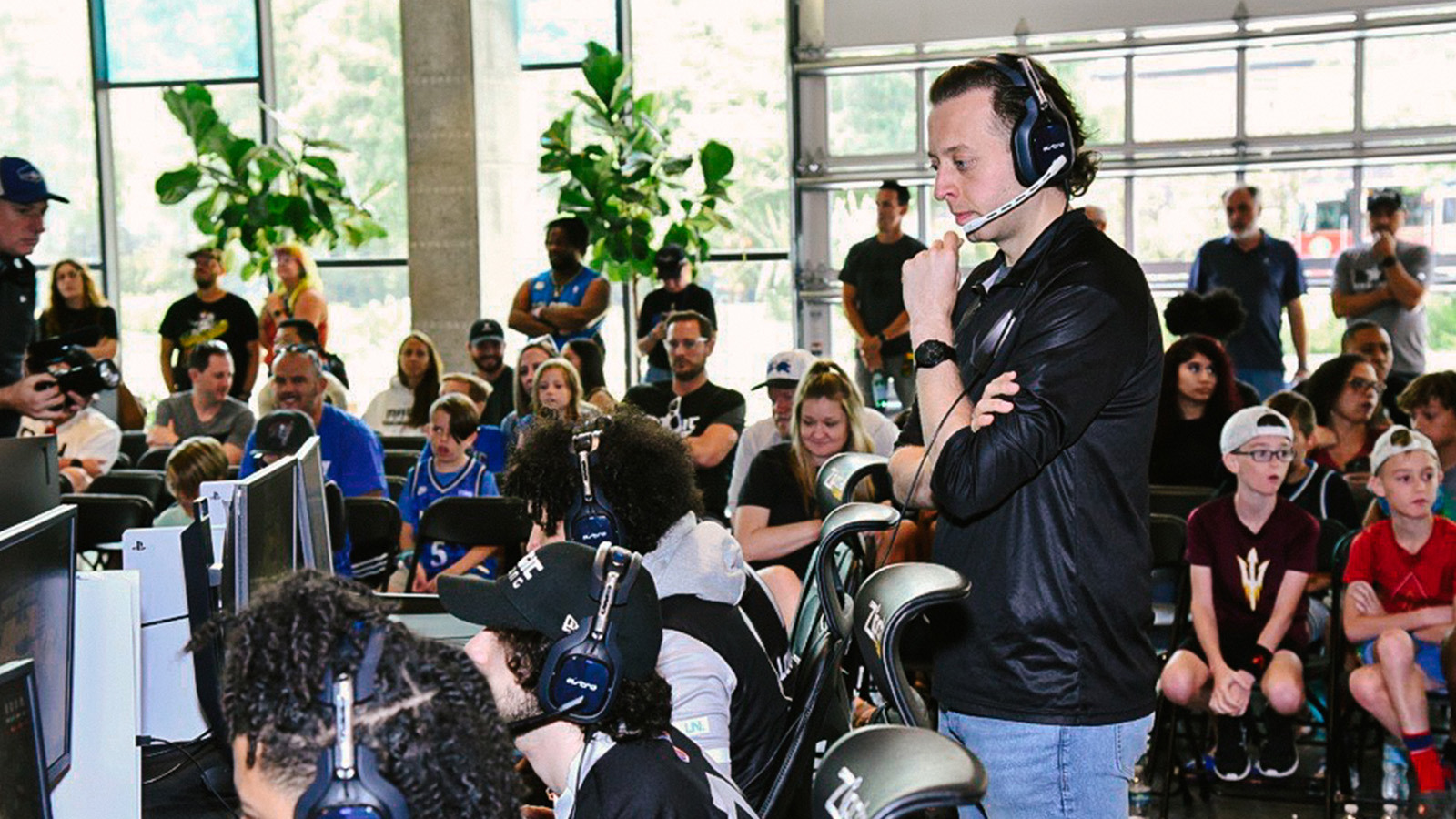 Magic Gaming’s coach and players at gaming stations while a crowd looks on in the background.