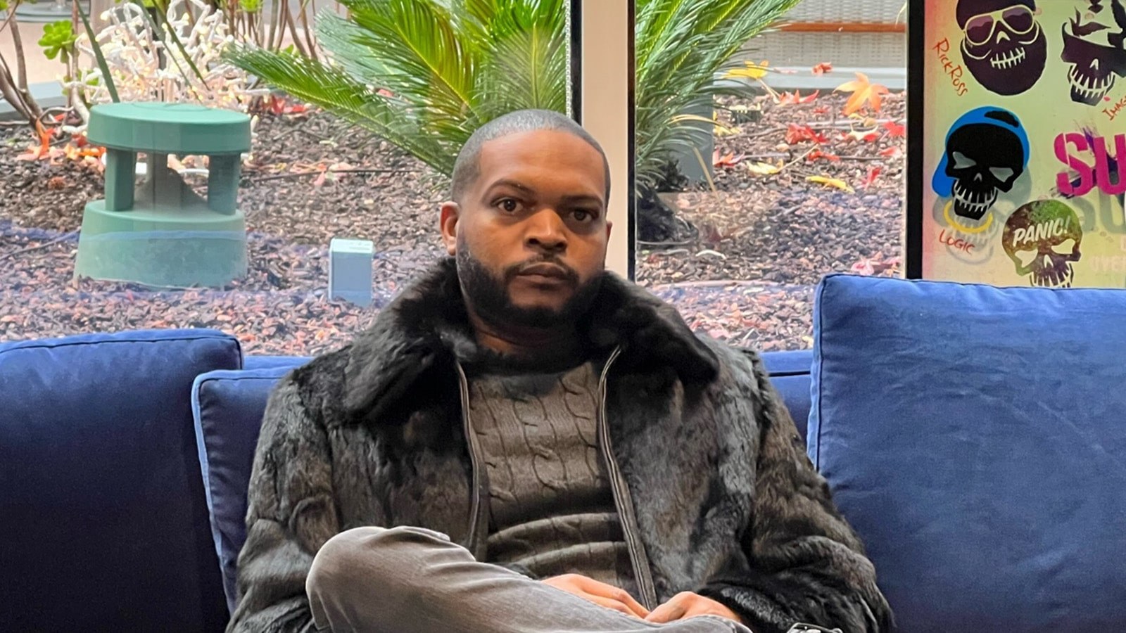 Terique Walker sits on a blue sofa wearing a black fur coat and turtleneck.