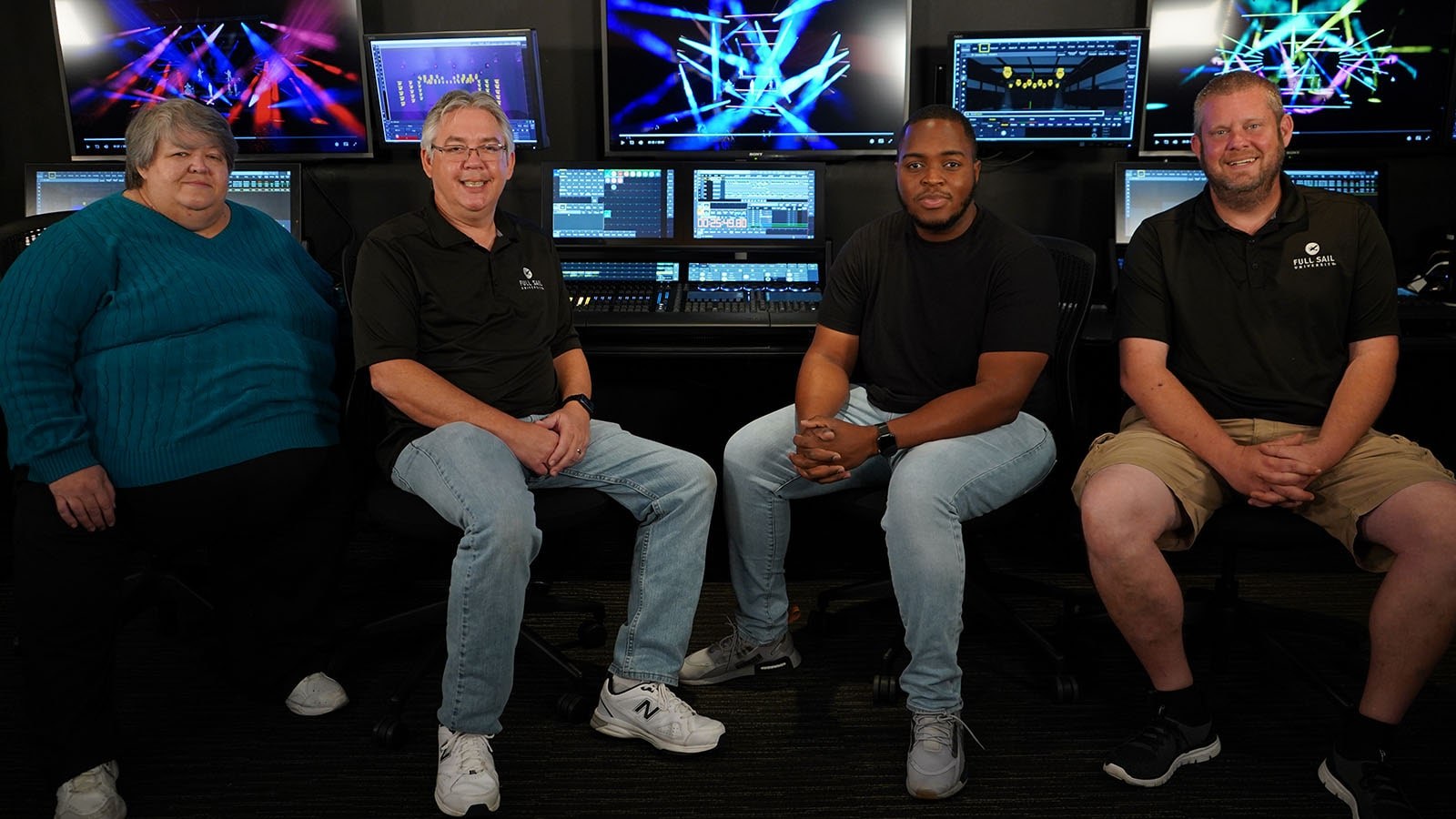 Four people sitting in front of a Grand MA lighting console at Full Sail University.