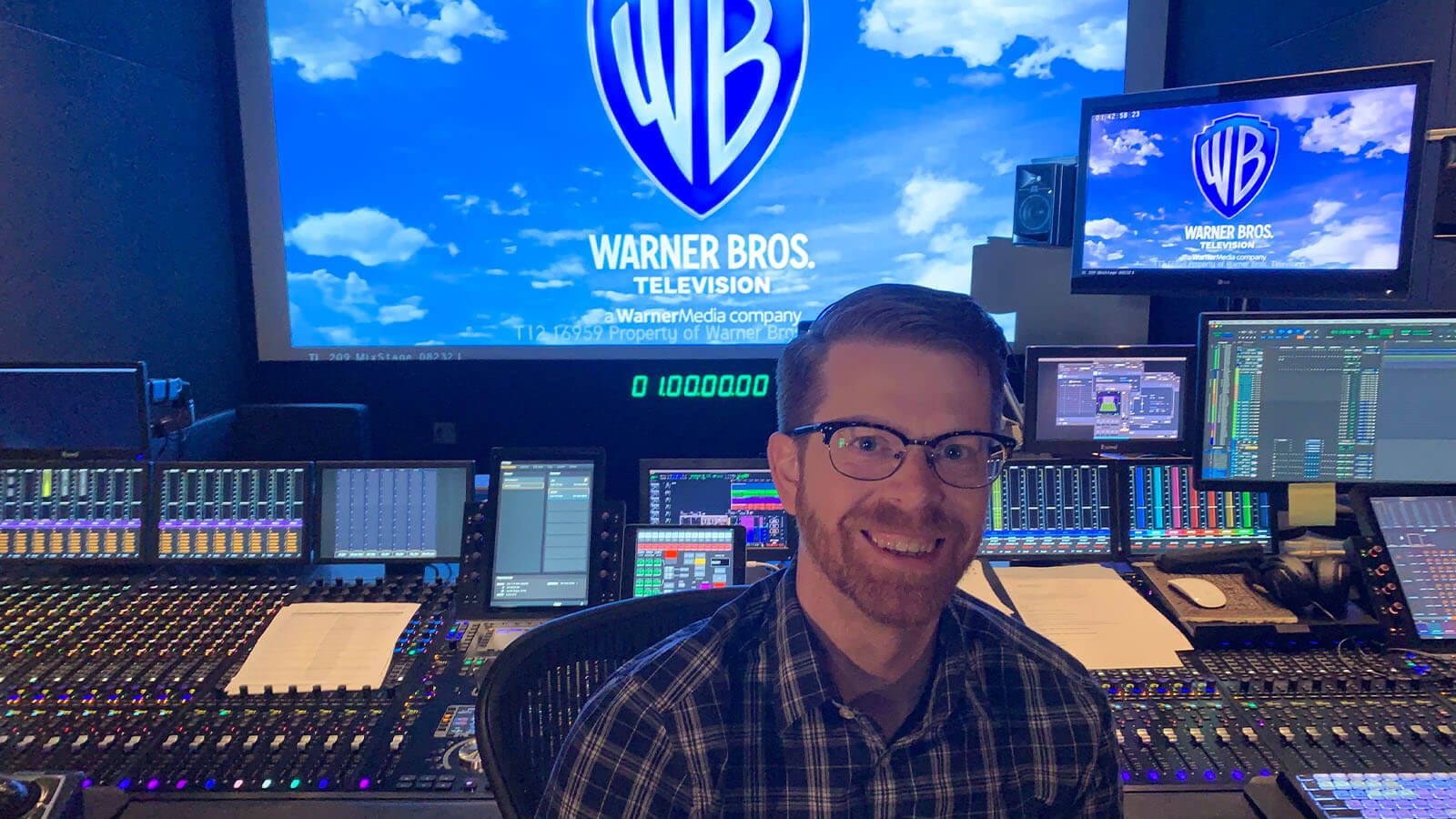 Recording Arts grad Ryan Kennedy sits in front of a large recording console.