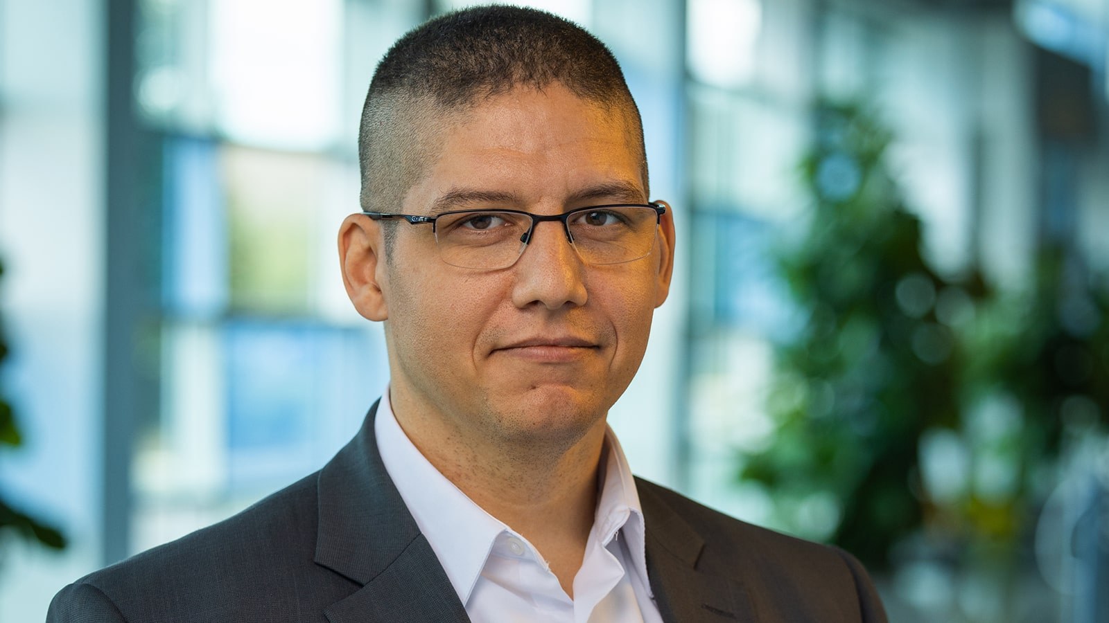 Mark Filter wears glasses, a gray suit, and a white button-down shirt. He is in one of Full Sail’s lobbies.