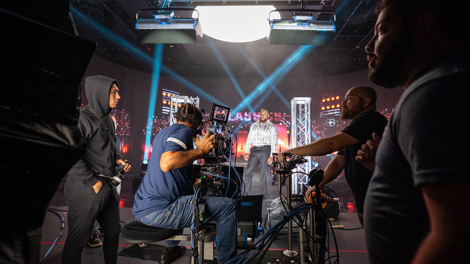 A camera crew films WWE Superstar Big E under bright stage lights for Netflix's RAW Classics at Full Sail University.