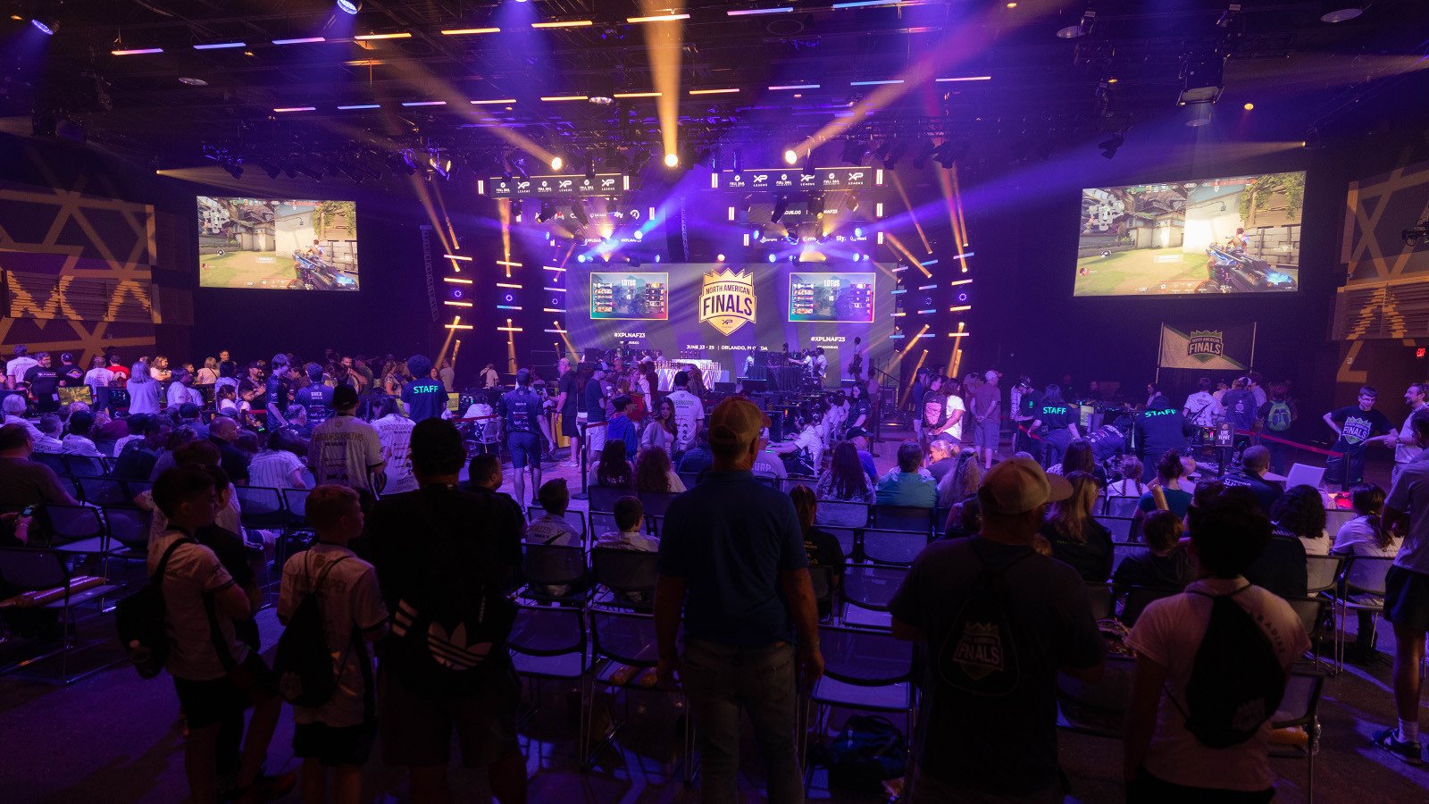 A large crowd in a venue spectating an esports match, a larg LED screen in the front of the room reads ‘North American Finals.’