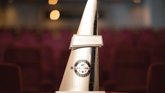 A triangular gold Sailee statue that says Full Sail University Hall of Fame with Full Sail’s logo.