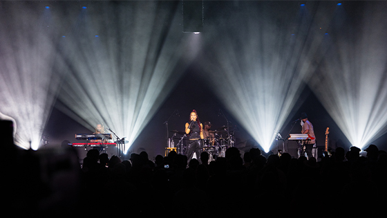 Crystal Kay performs under bright stage lights at Full Sail Live, backed by her band as the audience watches and records the show.