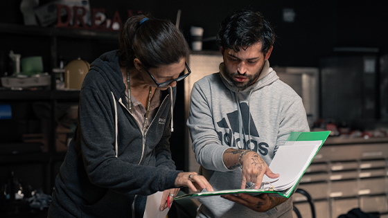 Deborah Walters helps student script supervisor Ryan Bessette with script on set