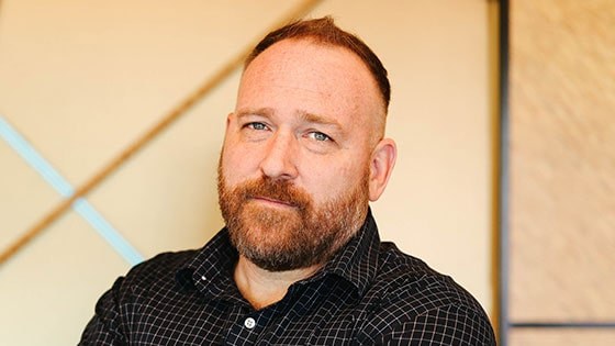 A shoulder-length photo of Ryan Little wearing a dark shirt standing in front of a light-colored background.