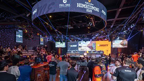 Students and alumni gather in the Fortress as Armada Varsity and Alumni team members compete. Screens show the Hall of Game: Homecoming logo.