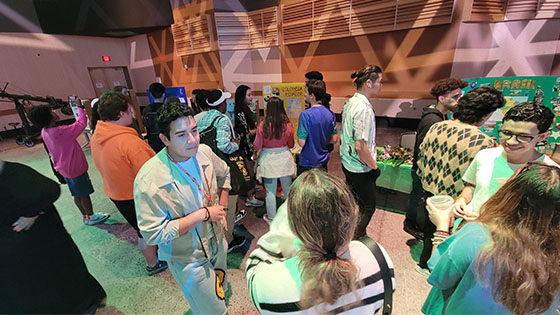 A crowd of people standing and talking around booths representing different countries at the Cultural Festival.