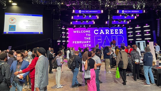 Students, alumni, and employers gather at the Full Sail Live venue for a career fair. A screen says, “Welcome to the February 12th Career Fair.”