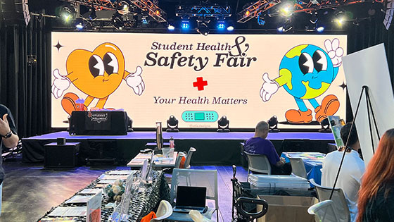 Screen in Full Sail’s The Fortress depicting an animation of a heart and an earth that reads “Student Health and Safety Fair” and “Your Health Matters.”