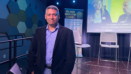 Rajiv Menon, founder of the Orlando Innovation League, poses in front of a stage at the Full Sail Treehouse.