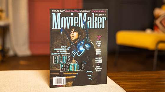 A copy of MovieMaker Magazine sits on a table. An actor in a Blue Beetle costume is on the cover. The headline “The 25 Best Film Schools & Coolest Film Festivals” runs across the top.
