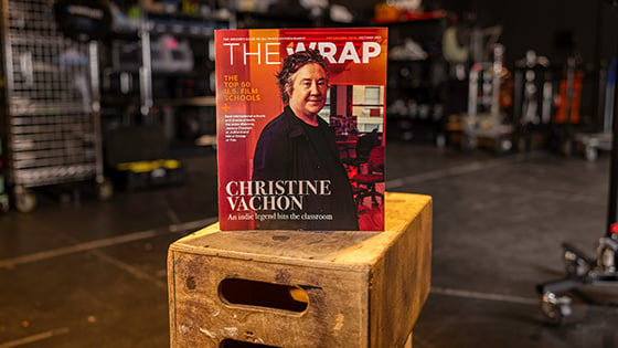 A physical copy of the October 2023 issue of 'TheWrap' is standing upright on a stack of wooden crates in a film studio setting.