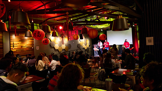 A group gathered at Full Sail's Treehouse, guests sitting down and the hosts on stage. The room is dimly lit and decorated with red paper lanterns for the Lunar New Year.