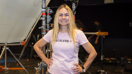 Director Sarah Goras stands confidently while smiling on set during filming in a Full Sail soundstage.