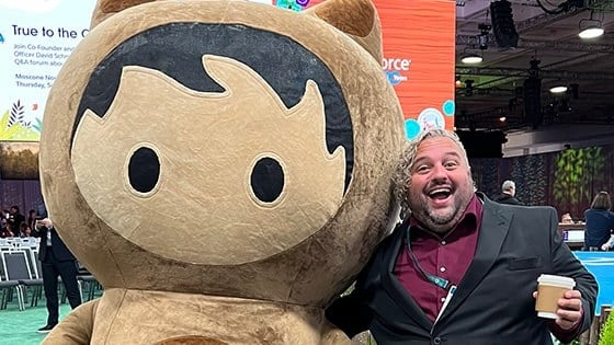 Adam Cipoletti stands with his arm around Astro Nomical, one of Salesforce’s mascots, at the Dreamforce conference.