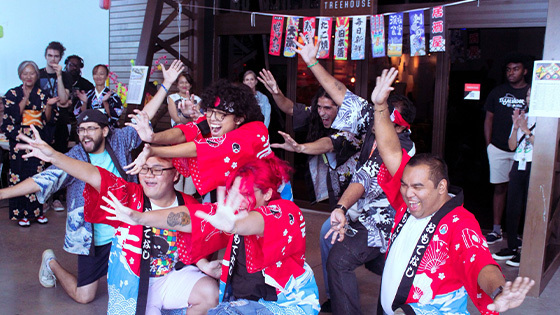 A crowd of students pose for the camera in front of the Treehouse wearing colorful traditional Japanese clothing.