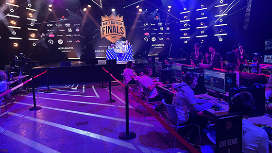 The stage in Full Sail’s Live Venue appears in the background of a row of players seated at gaming stations during the XP League North American Finals.
