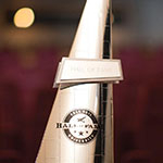 A gold, triangular statuette with the words Hall of Fame overlaid on the Full Sail University logo.