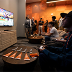 A room with gray walls and carpeting. The word Armada is written across the wall in white and several stations with gaming PCs are against the wall.