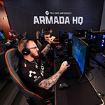 Gamers compete at Full Sail’s Armada HQ, celebrating a win in a high-energy esports match surrounded by teammates and gaming stations.