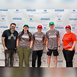 Five people posing in front of a “Seacrest Studios” backdrop, wearing Armada jerseys and hats, smiling at the camera.