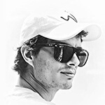 A black and white photo of Matias from the neck up, wearing a pair of sunglasses with dark frames while looking into the distance.