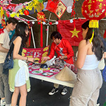 Students gather around a table to play a game at APIC’s night-market event.