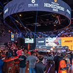 Students and alumni gather in the Fortress as Armada Varsity and Alumni team members compete. Screens show the Hall of Game: Homecoming logo.