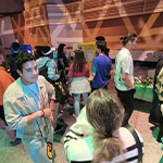 A crowd of people standing and talking around booths representing different countries at the Cultural Festival.