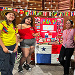A group of smiling students stand in front of a colorful exhibit about Panama.
