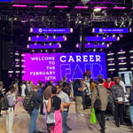 Students, alumni, and employers gather at the Full Sail Live venue for a career fair. A screen says, “Welcome to the February 12th Career Fair.”