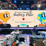 Screen in Full Sail’s The Fortress depicting an animation of a heart and an earth that reads “Student Health and Safety Fair” and “Your Health Matters.”