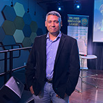 Rajiv Menon, founder of the Orlando Innovation League, poses in front of a stage at the Full Sail Treehouse.