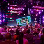 Full Sail Live, lit in a purple hue, is filled with a crowd seated at workstations during the Unreal Fest Game Jam.