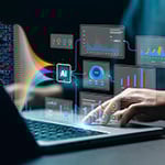 A close-up of a hand using a laptop. Colorful graphics of digital dashboards, charts, and a box saying AI are overlaid on the image.