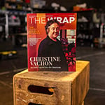 A physical copy of the October 2023 issue of 'TheWrap' is standing upright on a stack of wooden crates in a film studio setting.