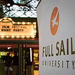 A Full Sail University banner is in focus in the foreground while the Enzian's lit-up marquee for the Florida Film Festival Opening Night Party appears in the background.
