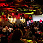 A group gathered at Full Sail's Treehouse, guests sitting down and the hosts on stage. The room is dimly lit and decorated with red paper lanterns for the Lunar New Year.