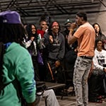 Artist performing with a microphone amidst a lively crowd.